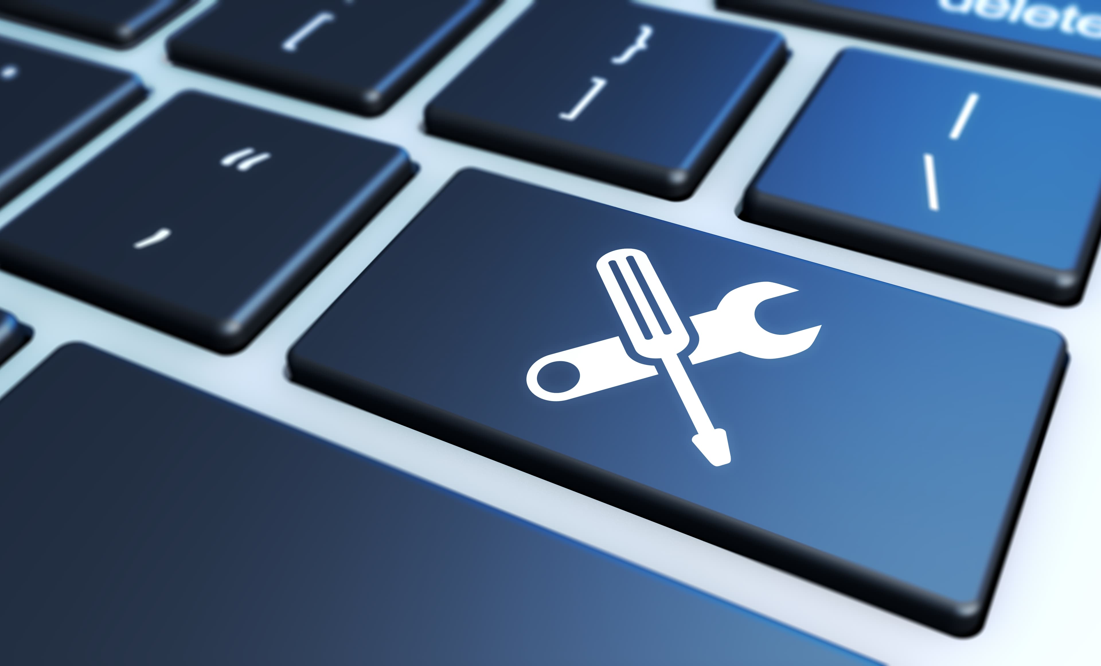 A close-up of a key on a computer keyboard. The key has overlayed icons of a screwdriver and a wrench.