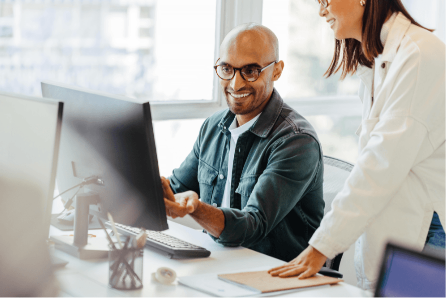 Man sitting at computer talking to woman